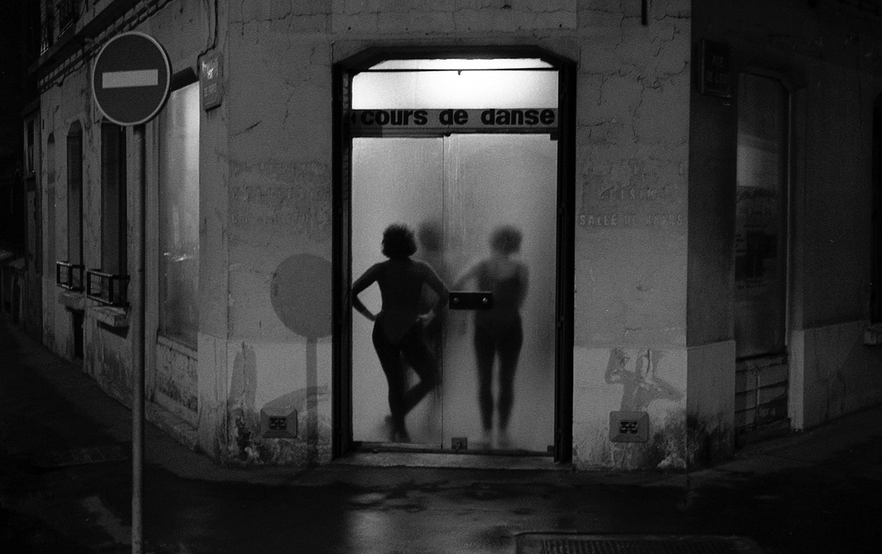 Les danseuses &ndash; Paris, rue de l'Est &ndash; Mars 1987
Encore une image pour Paris. Les petites danseuses de la rue de l'Est, par ce soir humide de fin d'hiver, sont comme un r&ecirc;ve de bonheur. A l'abri de tout, derri&egrave;re la porte vitr&eacute;e, dans la chaleur de la salle d'entrainement. Un Paris &agrave; la Robert Doisneau, une image un peu na&iuml;ve, un peu trop douce. Pendant longtemps, j'ai photographi&eacute; comme &ccedil;&agrave; la ville ou j'habitais. Plus tard, beaucoup plus tard, avant de quitter la capitale, j'ai train&eacute; dans les rues pour en saisir d'autres bribes, plus dures parfois, moins &eacute;videntes. Il n'emp&ecirc;che, j'aime encore bien cette image d'un Paris qui, plus que jamais a d&eacute;finitivement perdu son innocence.