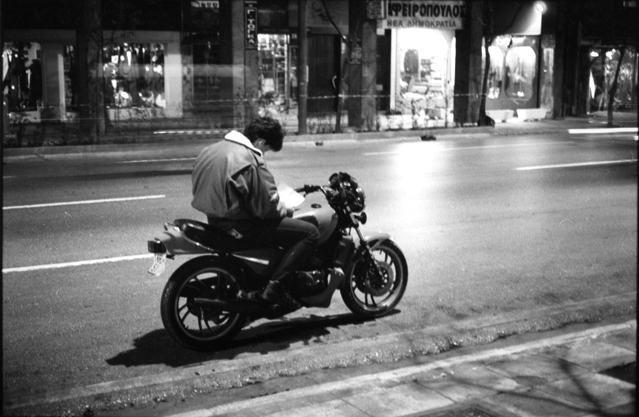 Solitude - Ath&egrave;nes, Gr&egrave;ce - Novembre 1988
Ce motard plong&eacute; en pleine rue dans sa secr&egrave;te lecture, je l'ai saisi un soir de novembre, il y a presque trente ans de cela. Est ce que les choses ont chang&eacute; &agrave; Ath&egrave;nes depuis cette &eacute;poque&nbsp;? Sans doute. La ville s'est incroyablement modernis&eacute;e, europ&eacute;anis&eacute;e, parfois au d&eacute;triment de sa singularit&eacute;. On roule d&eacute;sormais avec un casque, ce qui semblait inconcevable il y a trois d&eacute;cennies. Contrairement &agrave; ce que l'on voit sur cette image, la cit&eacute; grouille de monde, particuli&egrave;rement dans le centre-ville. Mais aujourd'hui, crise &eacute;conomique oblige, on ressent de la lassitude, du renoncement chez les grecs. Tristesse. Je quitte demain Ath&egrave;nes, pour un prochain retour &laquo;&nbsp;at home&nbsp;&raquo; apr&egrave;s un long s&eacute;jour. Un peu de tristesse aussi, donc.
