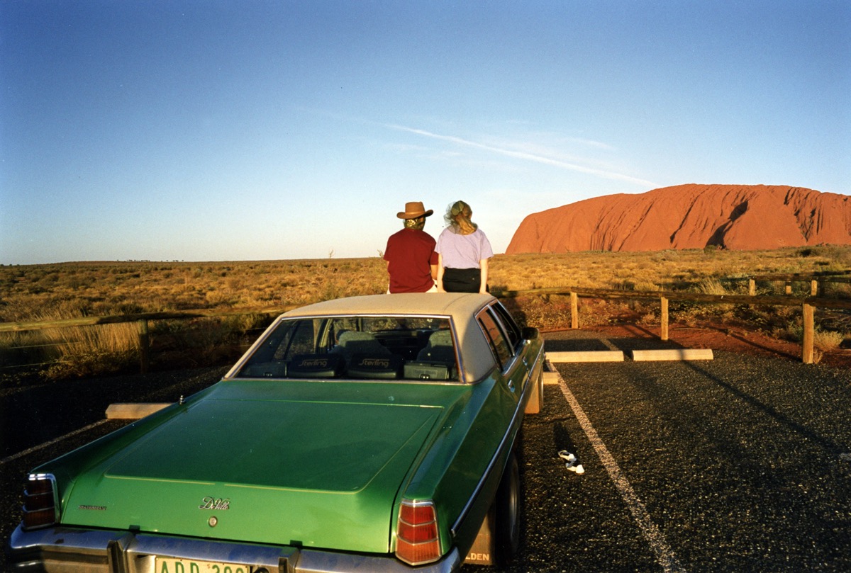 Uluru (Ayers Rock) Central Australia - Avril 1993 – Cette image a longtemps été un de mes «grands classiques» ;-) : le coucher de soleil sur le Rocher Rouge, les deux « Aussies » typiques (lui est coiffé d'un Akubra), la Holden Commodore verte comme dans les chansons de « Melbourne Aussie » de Charlélie Couture … Je me souviens encore du parking écrasé par la chaleur, des milliers de mouches du désert attirées par la présence humaine, mais aussi de nos voisins... car contrairement à ce que peut faire croire l'image, ce « spot » est incontournable pour voir le coucher de soleil sur Uluru. Résultat, le parking affiche souvent complet. Une dizaine d'années plus tard, nous sommes retournés au même endroit. Un serveur attendait les touristes auprès d'une table à la nappe blanche immaculée, bouteilles de champagne au frais ...
