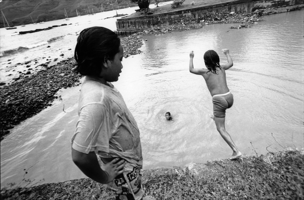 Les plongeurs – Raiatea, Polynésie Française – Mai 1993

Ah les petits plongeurs de Raiatea … Quelques instants auparavant, ils regardaient avec curiosité la chambre photographique que j'avais installée sur le quai de débarquement du copra. Ils n'avaient sans doute jamais vu un tel engin de leur vie. Ca avait créé des liens, et j'avais pu rester longtemps en leur compagnie pour saisir un de ces instants de grâce, au Leica cette fois. Parfois, les tropiques me manquent, la douceur du lagon, le « fiu », les geckos qui caquètent sous le toit du faré. Retournerai-je un jour là-bas, je ne sais. C'est loin tout ça.